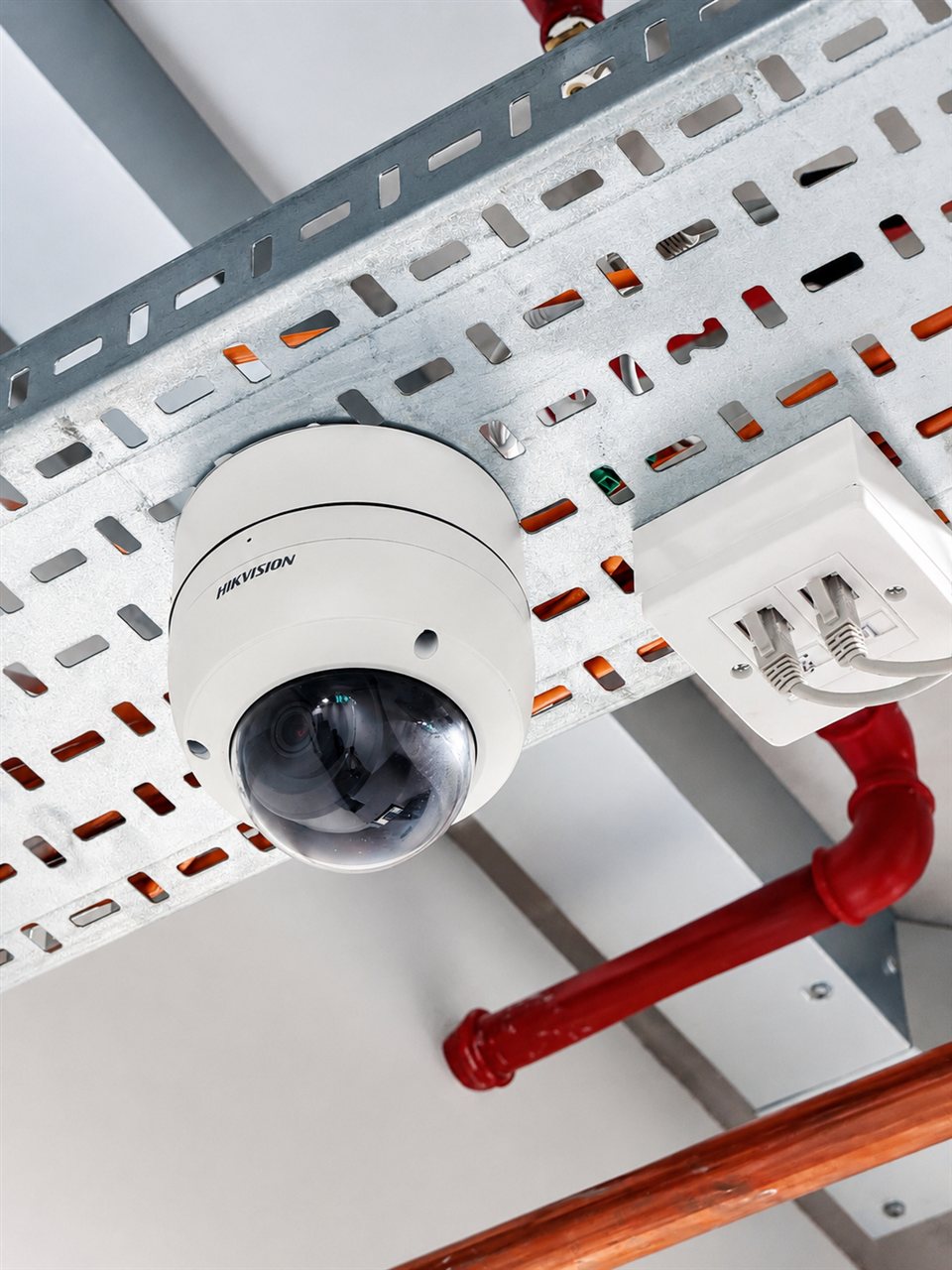 Hikvision dome CCTV camera mounted on a cable tray, connected via patch cabling