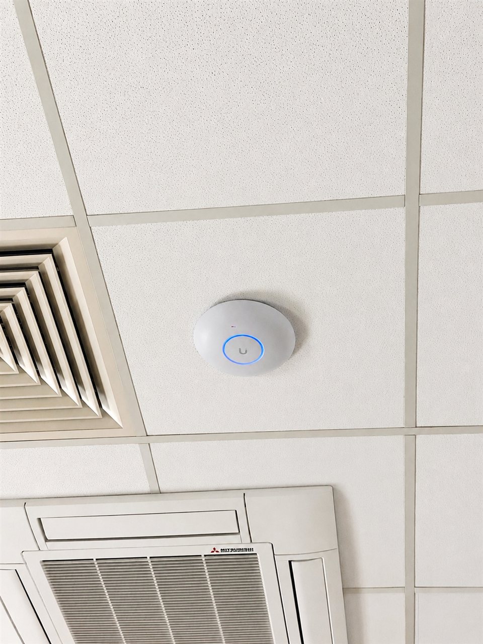 Ubiquiti wireless access point mounted on an office ceiling tile